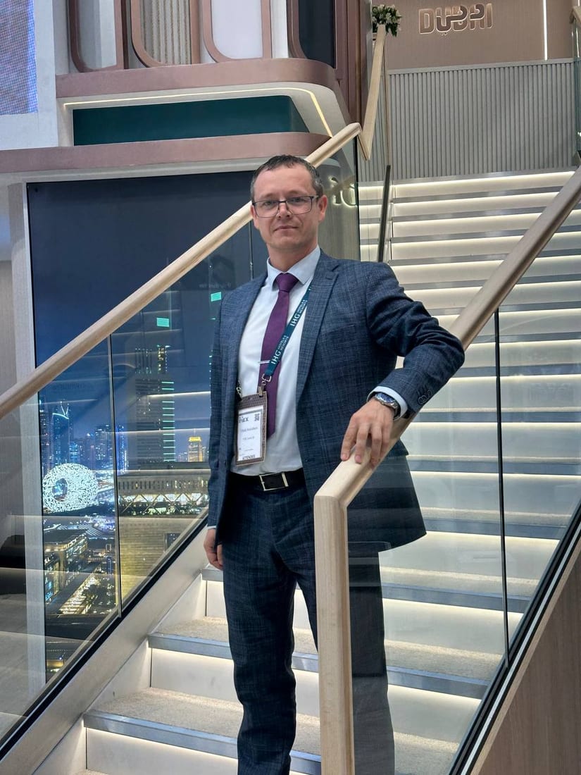 Vitalij Kolotikov, Unternehmer, Autor und KI-Dozent, auf einer Treppe mit der Skyline der Stadt im Hintergrund.
